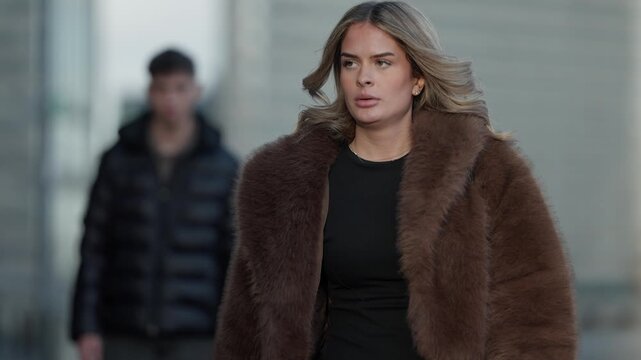 A woman in a fur coat walks past a man in Paris France Panning shot of a couple in love The fashionable woman walks in the city Romance relationship and lifestyle.