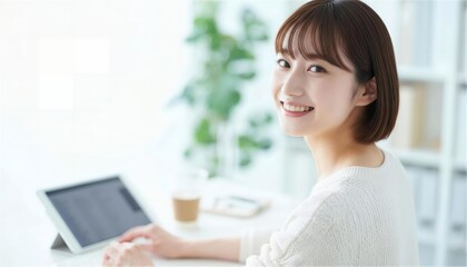 タブレット作業中に振り返って微笑む白いニットの女性