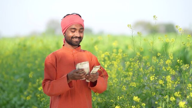 Young indian farmer counting money at agriculture field