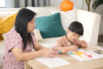 A mother and child spending quality time together, engaged in a creative drawing activity. The mother is attentively assisting her child as they draw on paper with colorful markers