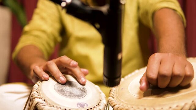 Close-up of an artist playing tabla, highlighting traditional Indian percussion, rhythm, and cultural music performance with detailed hand movement on the drum surface.