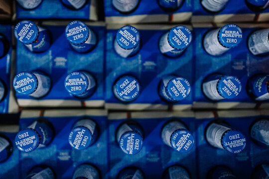 Blue bottle caps of Birla Moretti Zero arranged in a grid pattern on a blue background for beverage display or marketing