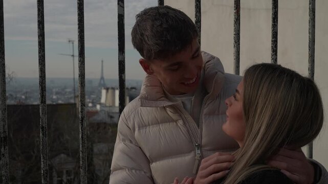 A young couple embraces affectionately with the Eiffel Tower visible in the background in Paris France The lovers are hugging showcasing a romantic moment with the Parisian cityscape as a backdrop.