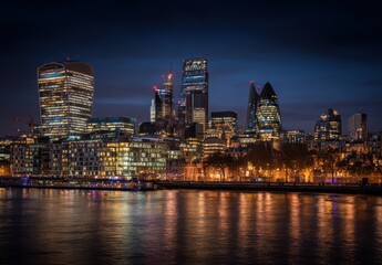 Fototapeta premium Illuminated Cityscape At Night With River Reflection And Tall Buildings In London England