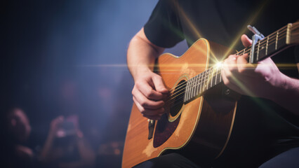Naklejka premium Acoustic Guitar Performance Musician Playing on Stage with Audience in Background