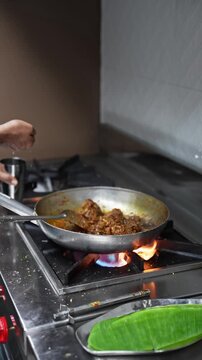 Cook adds water to mutton chaap, causing flames to rise under the pan.