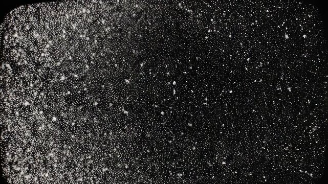 A textured black surface filled with tiny white specks, resembling a starry night