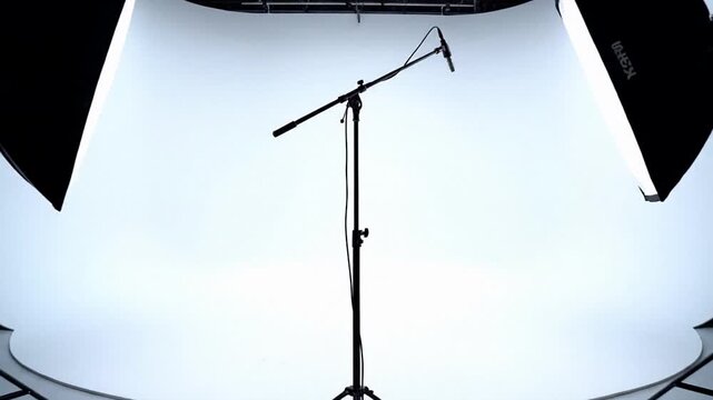 Photo studio setup with softbox lights and microphone stand on white backdrop, professional production workspace for filming and podcasts, clean modern creative mood