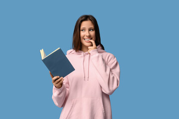 Obraz premium Thoughtful young woman with notebook on blue background