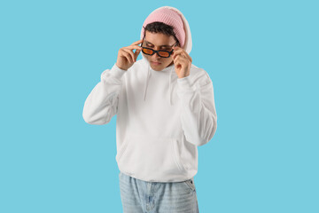 Stylish young man in white hoodie on blue background