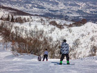 Three snowboarders enjoying the scenic view of snow-covered trees and mountains in winter