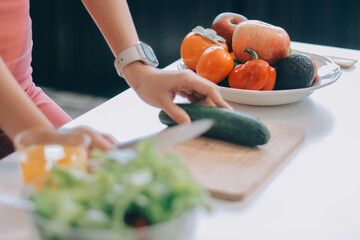 Fit young Asian women in activewear sitting on yoga mat and eating fresh vegetable salad after workout, representing clean eating, fitness lifestyle, wellness routine and health balance.