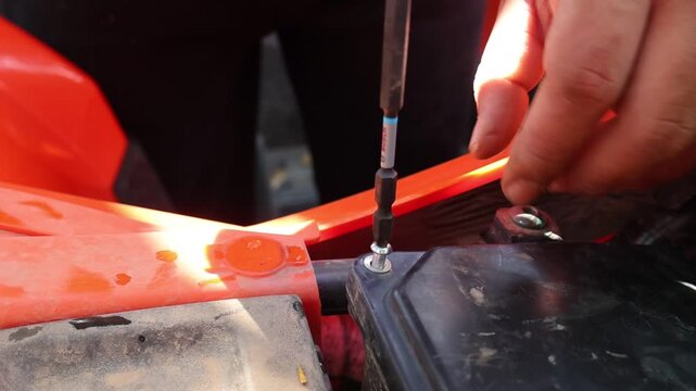 Focused mechanic hand using screwdriver tool for vehicle repair and maintenance work. Detailed manual labor involves technical job of fixing crucial screw during service