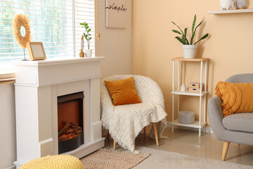 Naklejka premium Fireplace and armchair near beige wall in interior of living room, closeup