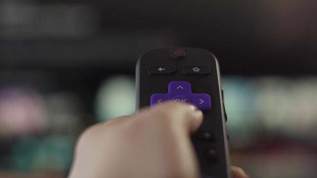 Person browsing and selecting content on a streaming service with a remote control, choosing a movie or show to watch