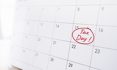 A calendar with the words &ldquo;Tax Day&rdquo; written in red on a specific date. Concept of tax deadline, income tax payment.