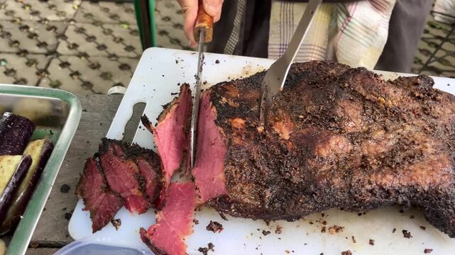 Man slicing a loaf of smoked brisket pastrami on a cutting board, with fun vibes