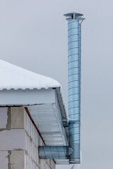 A metal pipe is attached to the roof of a building