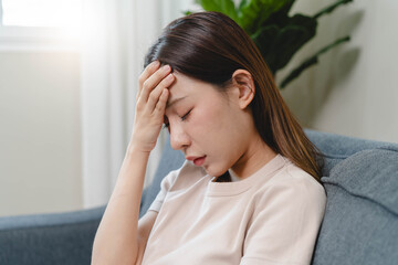 Fototapeta premium Asians female in stressed expression sitting on the sofa in the house.