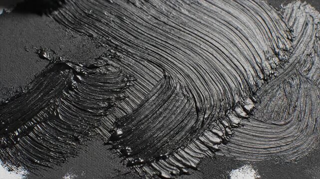 Close-up view of abstract black and white brush strokes on canvas, capturing dynamic movement and texture from a frontal perspective