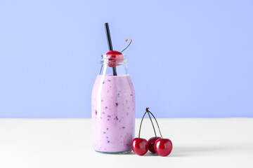 Bottle of fresh smoothie with cherries on blue background