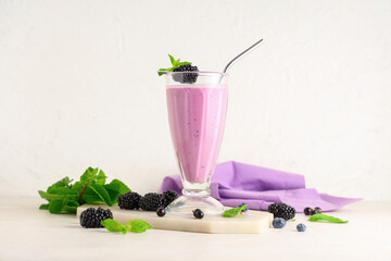 Glass of fresh smoothie with blackberries, black currant and blueberries on white background