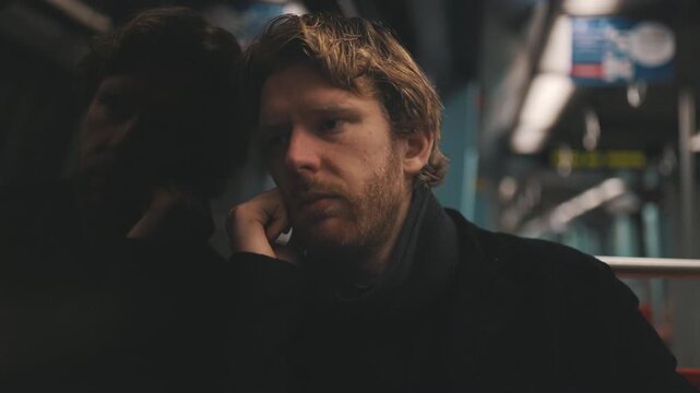 Melancholic man traveling alone on subway train at night