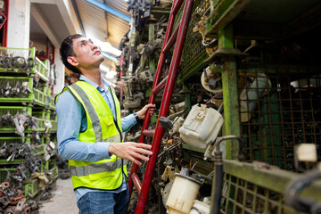 Worker examining parts on a shelf in a storage facility © offsuperphoto