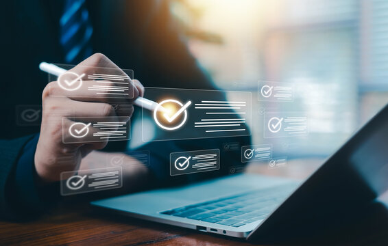 Business professional using digital checklist and virtual approval interface on laptop, concept of quality control, compliance management, workflow automation, and business technology innovation.