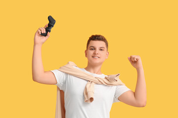 Teenage boy with game pad celebrating success on yellow background © Pixel-Shot