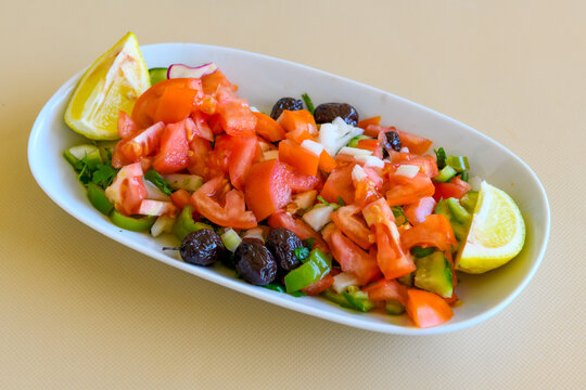 Green salad with arugula, lamb and tomatoes. Healthy vegan dish. Top view at table. Turkish Coban (choban) salata or Shepherds salad, Akdeniz salad in white bowl.