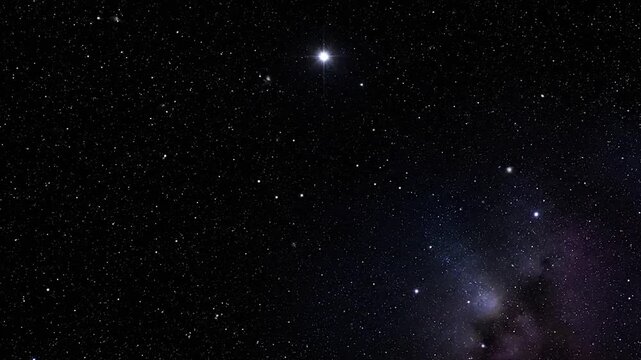 A dark night sky with numerous bright stars and a faint nebula in the bottom right corner
