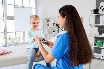 Obraz premium Female pediatrician taking pulse from little girl in clinic