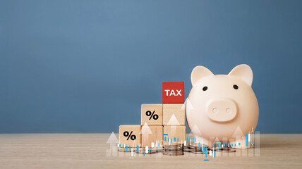 Piggy bank with wooden blocks showing tax and percentage symbols on table with upward financial chart overlay. Concept of tax planning