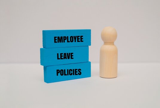 A wooden figure next to stacked colorful blocks with EMPLOYEE LEAVE POLICIES text. Human resources, benefits and workplace regulations content concepts
