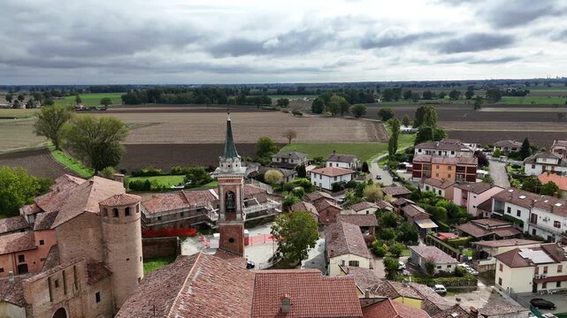 Calendasco village with the Castello di Calendasco and the Church of Santa Maria Assunta and its bell tower, surrounded by agricultural fields in the Po Valley, Piacenza, Emilia-Romagna, Italy.
