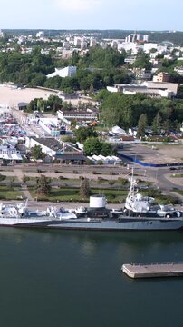 High angle aerial shot of the historic ORP Blyskawica destroyer docked in Gdynia marina, Poland, featuring the city skyline and coastal landscape.