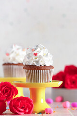 Stand with tasty cupcake, rose flowers and sprinkles for Valentine's Day on table