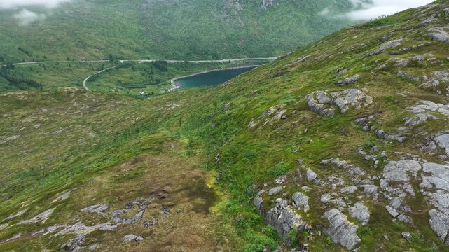 Aerial, forward drone flight above Norwegian mountains, trail to Barden mountain. Hikers with two dogs near small pond. Small lake and hiking parth in distance. Senja island in Norway. Beautiful lands