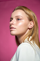 Fototapeta premium A large portrait of a woman with light gold hair and sky-blue eyes. She is wearing a white shirt and is staring straight ahead.