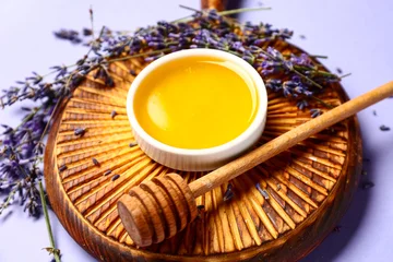 Fotobehang Eten Wooden board with bowl of sweet lavender honey, dipper and flowers on blue background  © Pixel-Shot