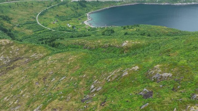 Aerial, forward turn drone flight above Norwegian mountains, trail to Barden mountain. Grassy mountain slope with rocks. Small lake and hiking parth in distance. Senja island in Norway. Beautiful land