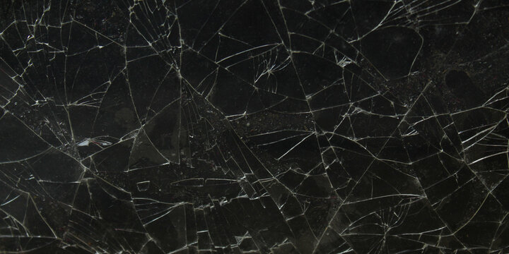 a black glass screen that is cracked and shattered into pieces on a dark background