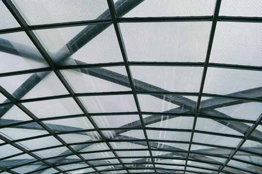 Modern glass roof canopy with steel grid structure forming repeating pattern and perspective lines in contemporary architecture for transport background