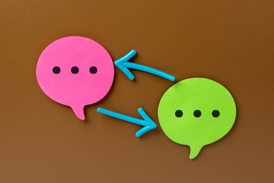 Pink and green speech bubbles are connected by two  arrows. Feedback loop and iterative communication cycle concept.