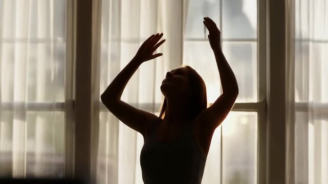 Silhouette of a woman stretching her arms up high by the window, sun flare, stiff shoulder relief, wellness concept, unrecognizable, 4k