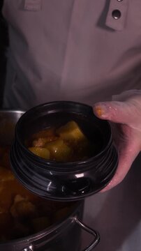 Potato and meat goulash. The cook puts delicious goulash in ceramic dishes.