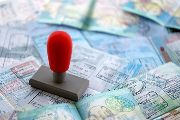 Border crossing stamp on big amount of passport pages full of colorful stamps after travel and...