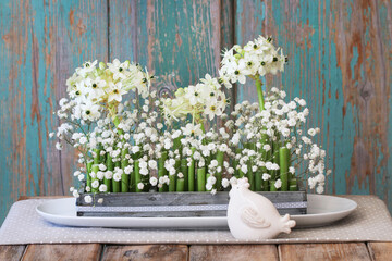 Florist at work: woman shows how to make Easter floral table decoration with arabian star flowers and gypsophila paniculata twigs in simple wooden box. Step by step, tutorial.