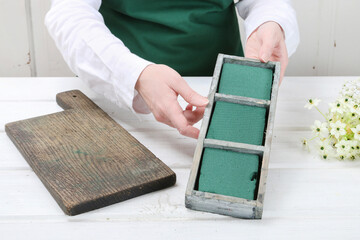 Florist at work: woman shows how to make Easter floral table decoration with arabian star flowers and gypsophila paniculata twigs in simple wooden box. Step by step, tutorial.